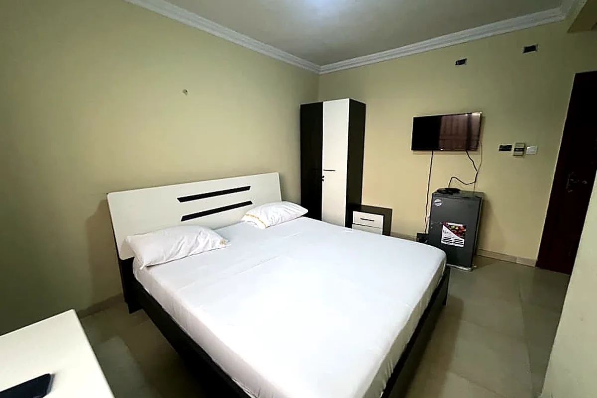 Chambre double équipée d’une télévision, d’une armoire et d’un réfrigérateur